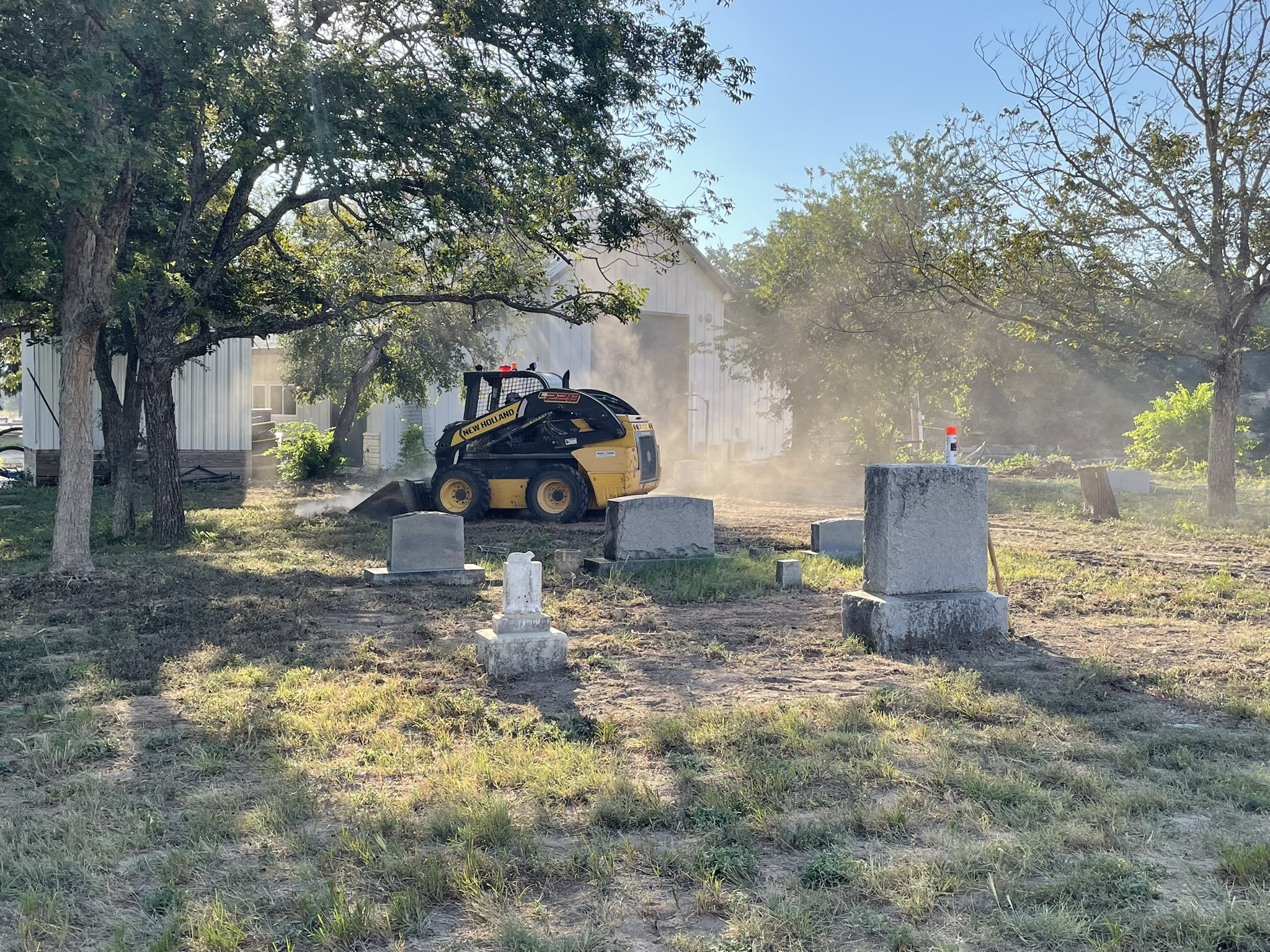 Southern Landscapes skid-steer moving dirt among headstones
